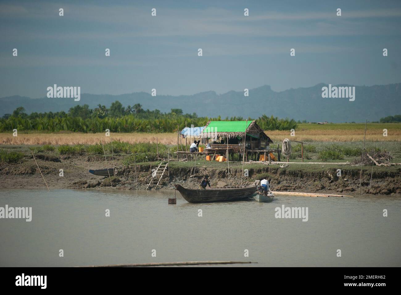 Myanmar, Birmania occidentale, Mrauk U, capanna di palafitte e barca sul fiume Foto Stock