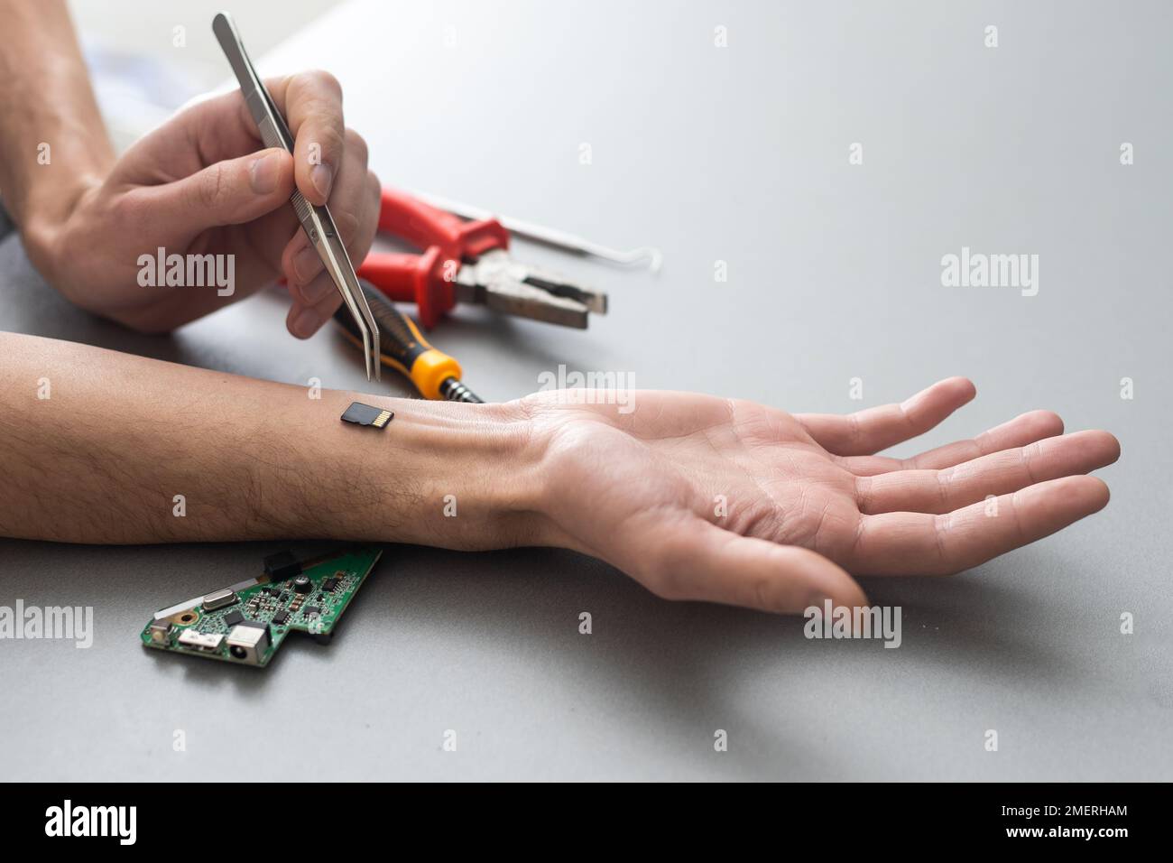 Concetto del braccio del robot. L'uomo mostra una mano biomeccanica protesica. Guy ripara la mano con l'attrezzo. Bioingegneria, transumanesimo, biohacking, cyborg umano Foto Stock