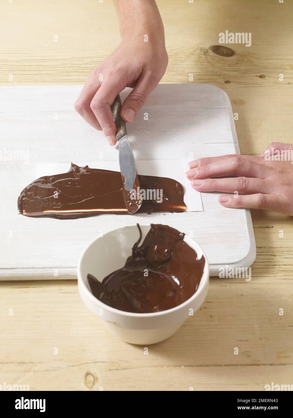 Spalmare il cioccolato su carta antigrasso, facendo il cilindro di cioccolato Foto Stock