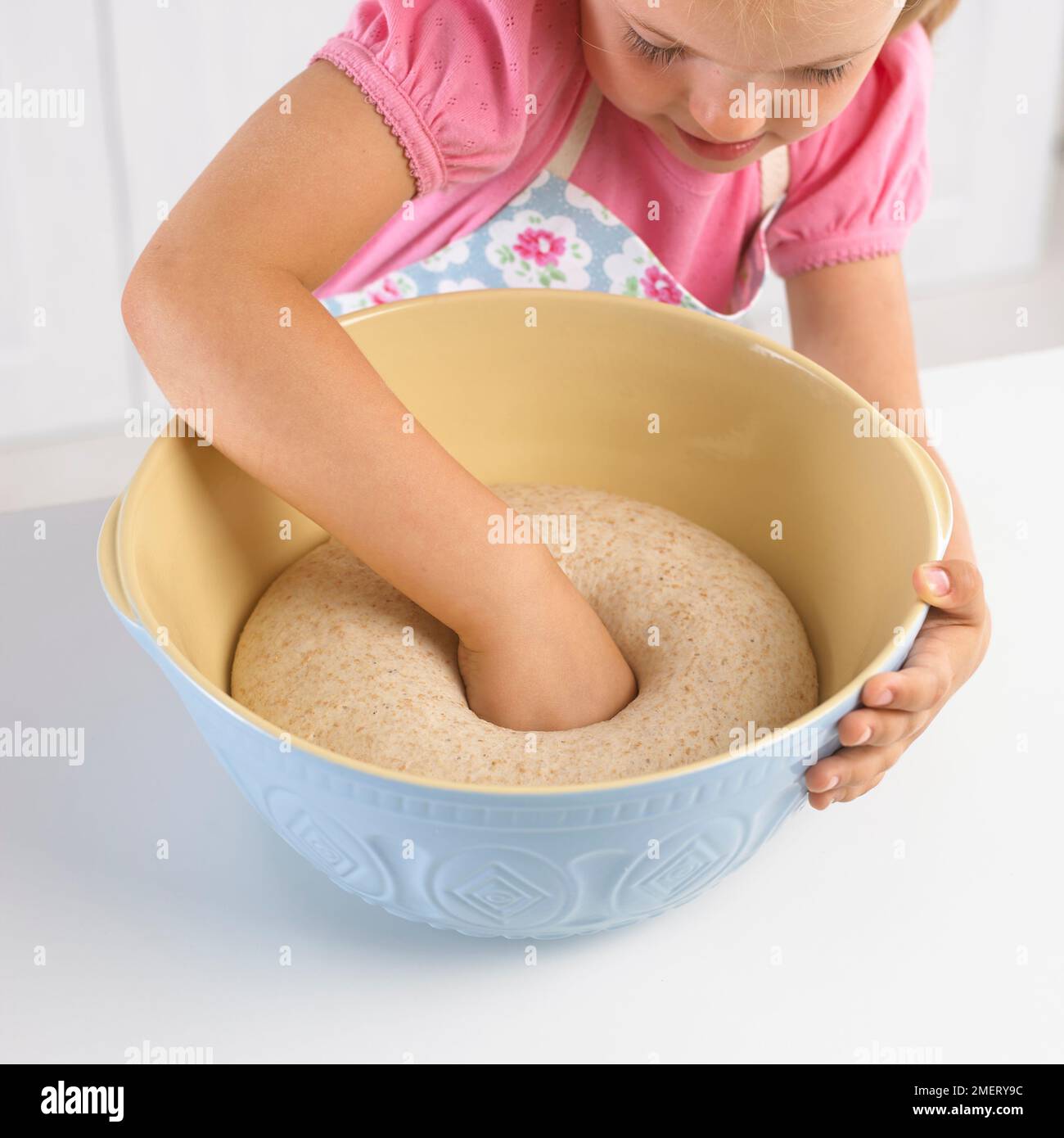 Ragazza che bussa indietro la pasta resuscitata con le sue nocche punzonandola giù, 5 anni Foto Stock