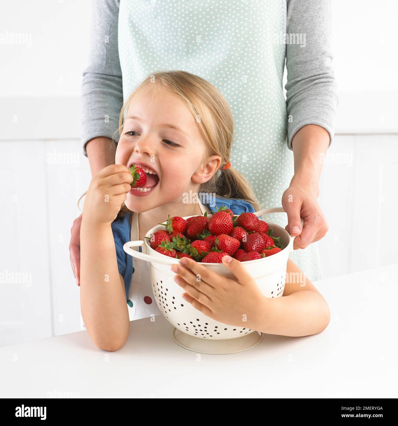 Ragazza con scolapasta di fragole, 5 anni Foto Stock