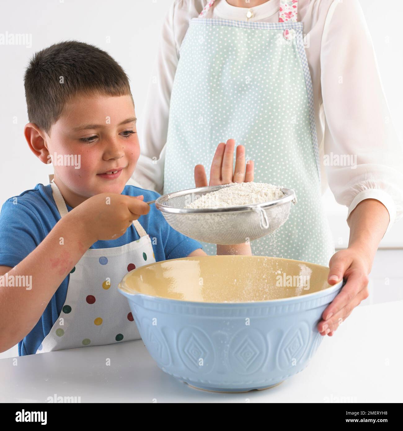 Setacciare la farina in un recipiente per mescolare, 7 anni Foto Stock
