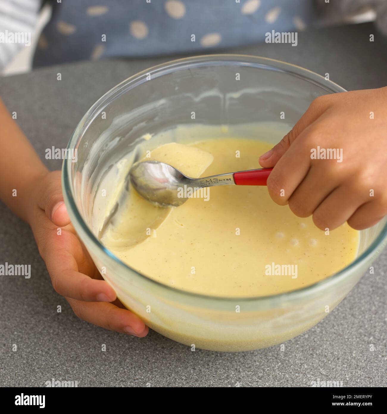 Ragazzo (4 anni) utilizzando un cucchiaino da tè, raccogliendo bocconcini di miscela di cioccolato, facendo tartufi di cioccolato Foto Stock