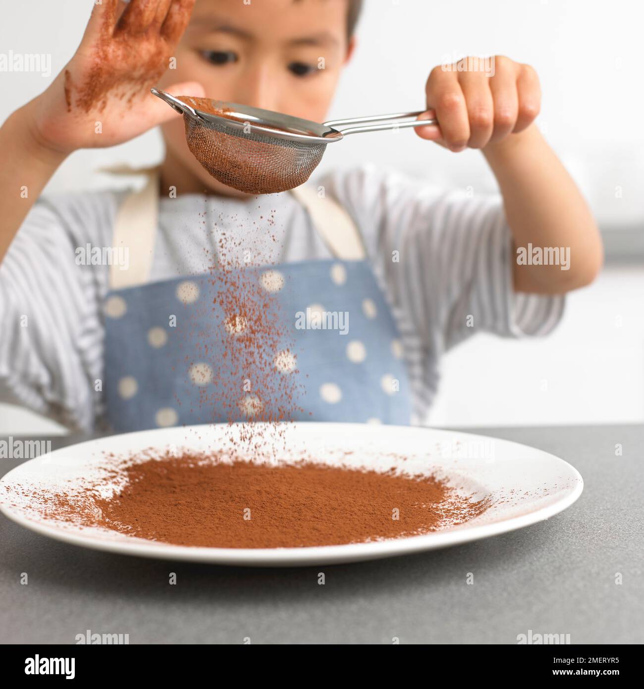 Polvere di cioccolato setacciante, 4 anni Foto Stock