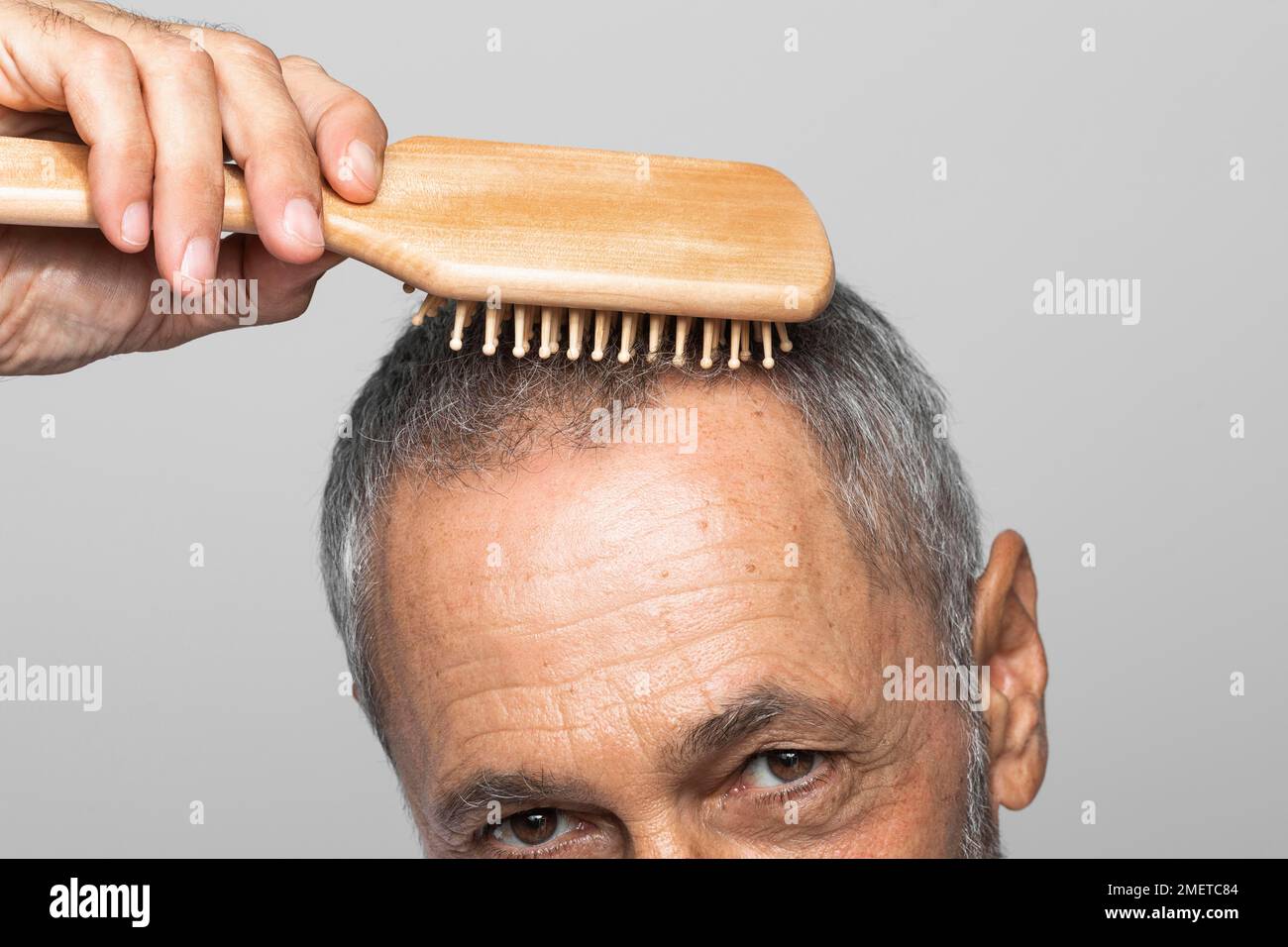 Primo piano uomo anziano spazzolando i capelli Foto Stock