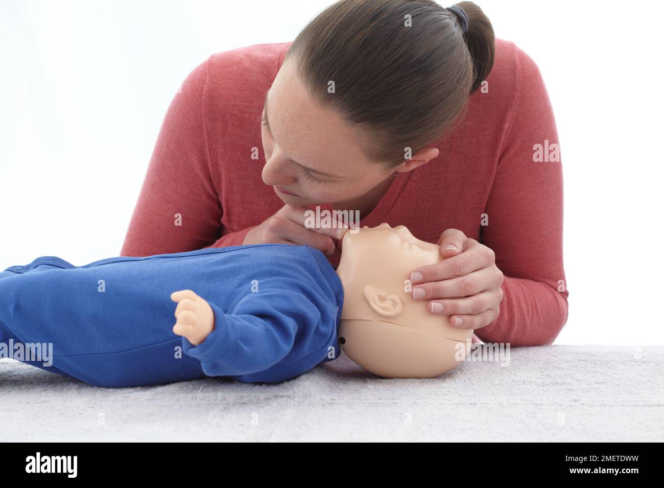 Controlli medici di primo soccorso e trattamento del bambino inconscio, utilizzando manichino, dando CPR, togliendo la bocca del bambino e vedendo se il suo petto cade, mantenendo l'inclinazione della testa e il sollevamento del mento Foto Stock