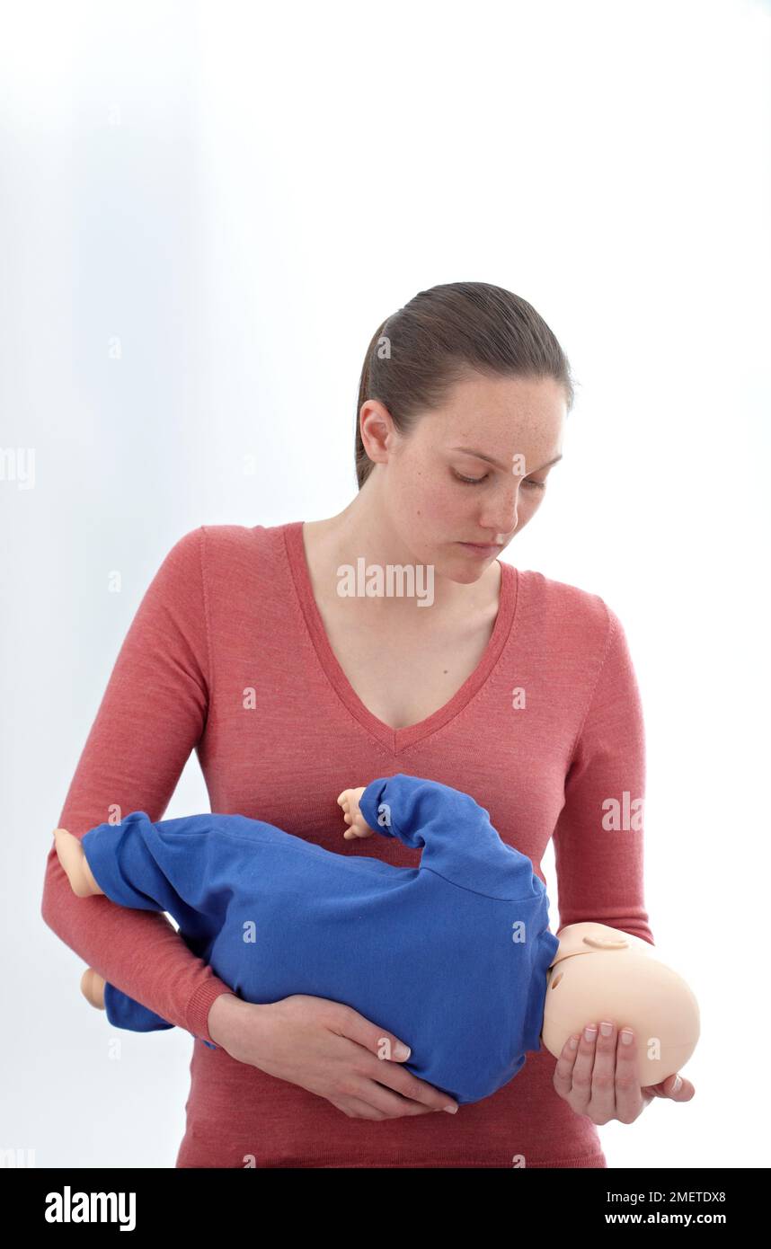 Controlli medici di pronto soccorso e trattamento del bambino inconscio, utilizzando manichino, tenendo in posizione di recupero Foto Stock