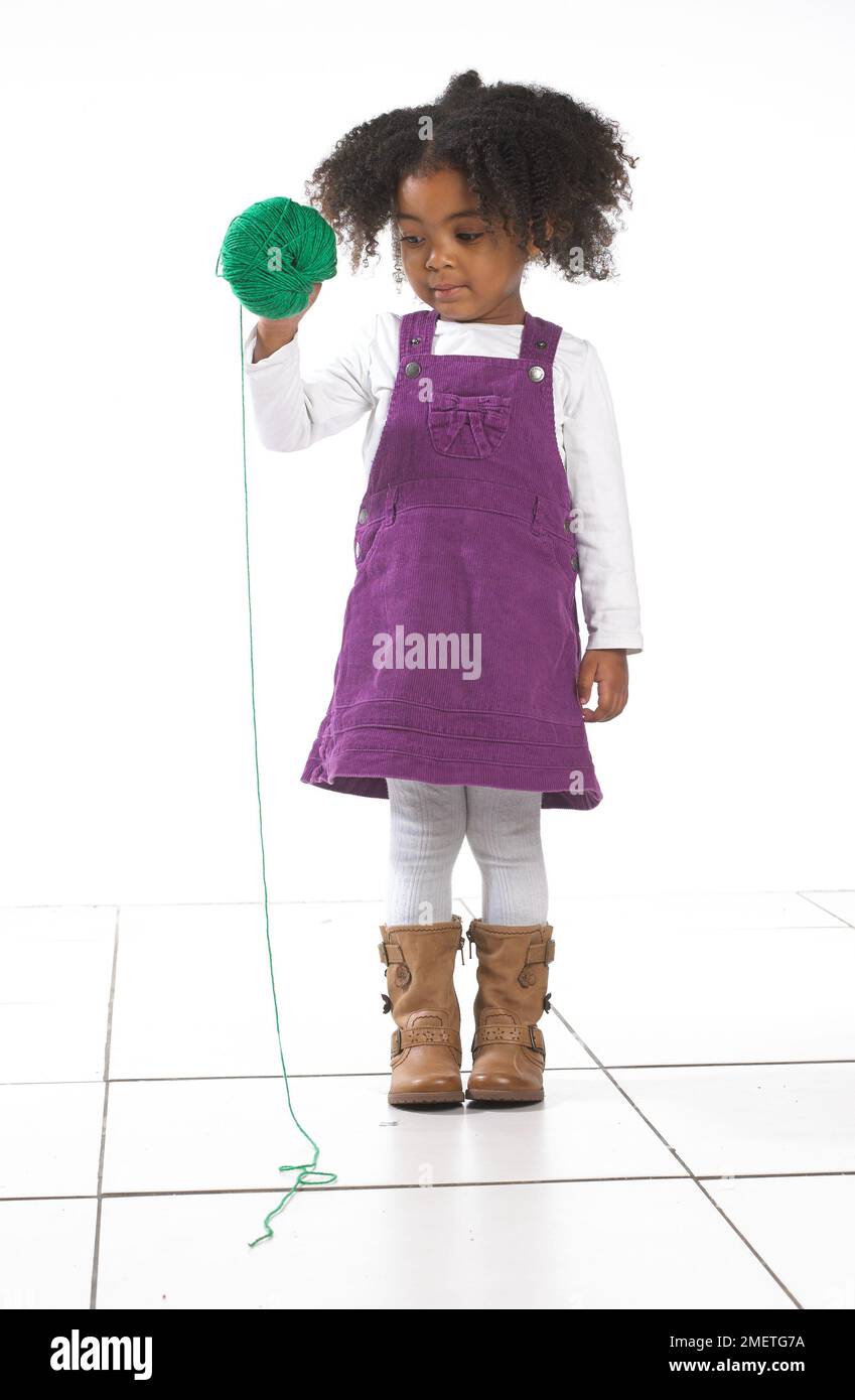 Ragazza in piedi tenendo palla di lana, 3 anni Foto Stock