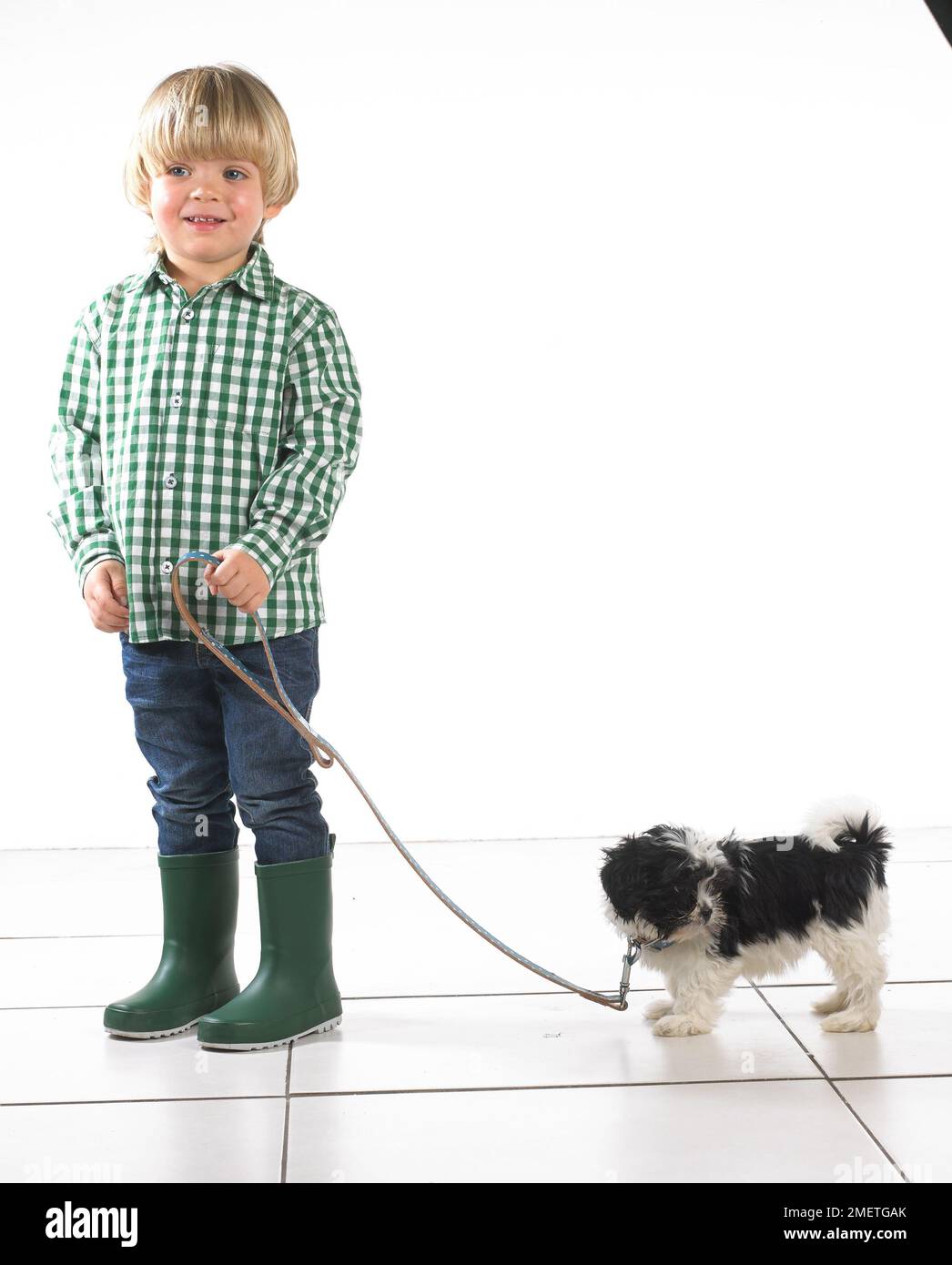 Giovane ragazzo che tiene il cucciolo al piombo, 2 anni Foto Stock