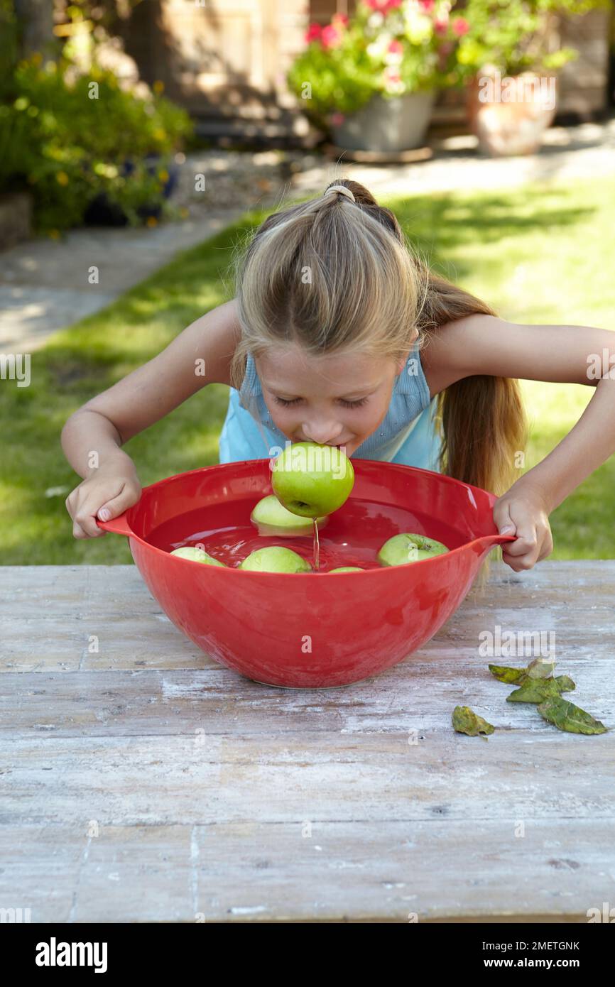 Ragazza che gioca apple bobbing gioco Foto Stock