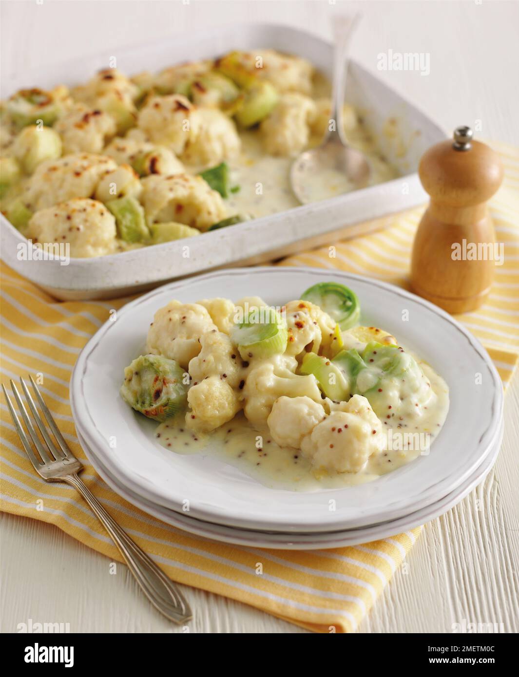 Cavolfiore con porri e senape grinosa, in teglia e su piatto, pepperino nelle vicinanze Foto Stock