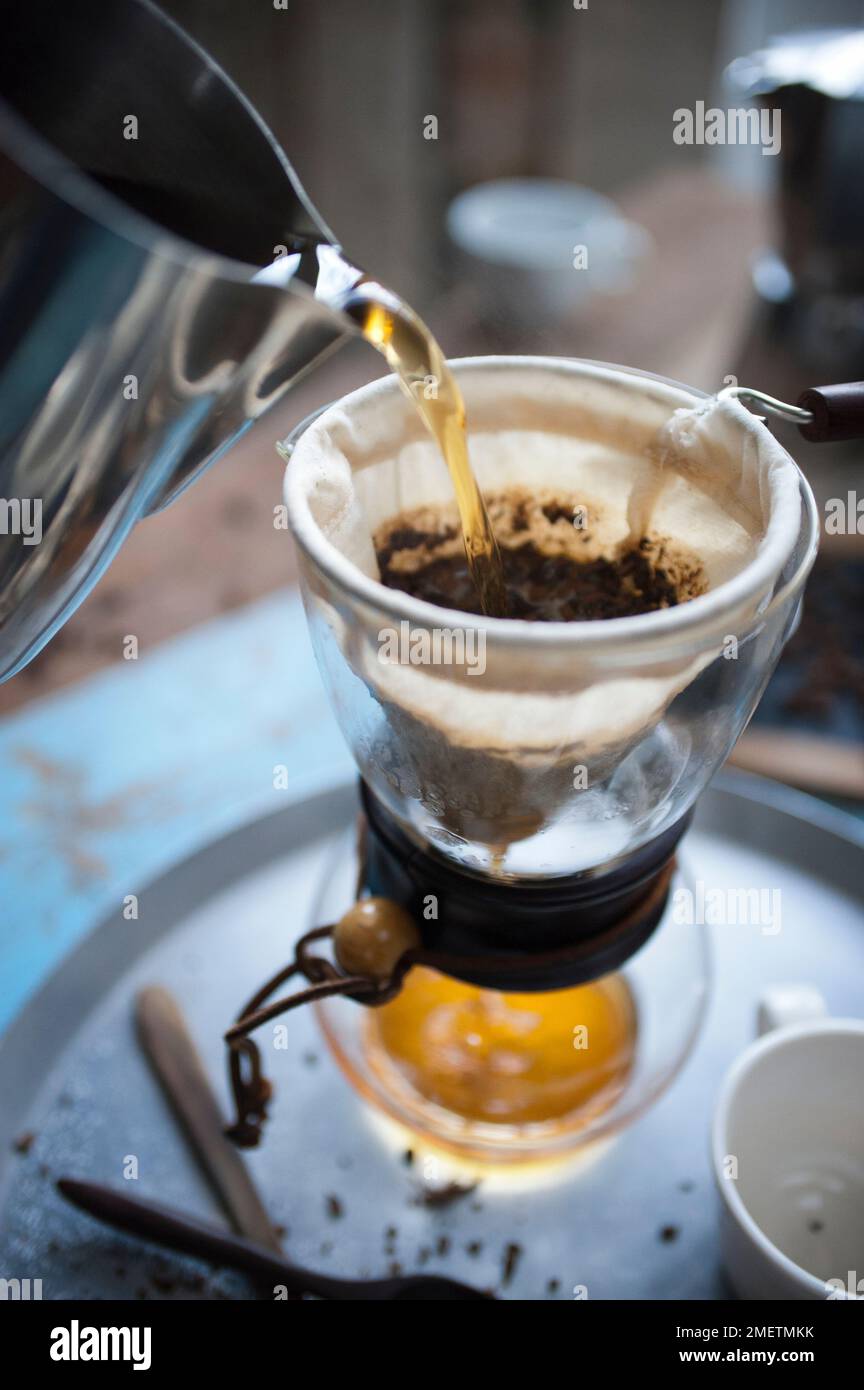 Caffe Touba, versando acqua calda nel caffè, scaricando attraverso un panno nella caraffa di vetro Foto Stock