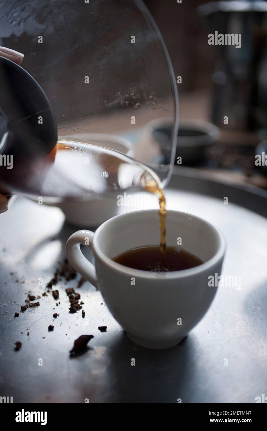 Caffè Touba, versare il caffè da una caraffa di vetro nella tazza Foto Stock