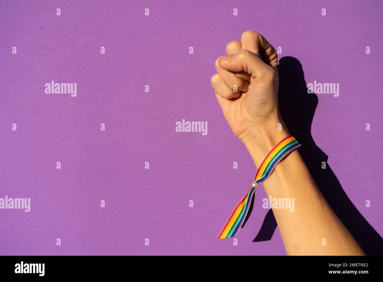 Mano di una donna con pugno chiuso in simbolo femminismo a favore del femminismo, sfondo viola, lotta a favore delle donne, forza femminile, bandiera LGTB Foto Stock