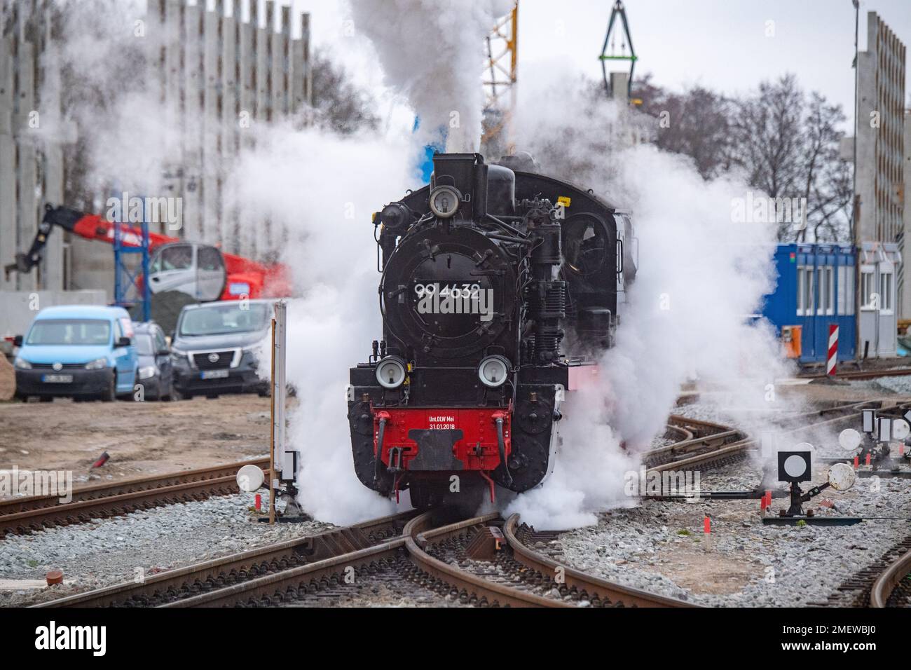 24 gennaio 2023, Meclemburgo-Pomerania occidentale, Putbus: La locomotiva a  vapore 99 4632 della piccola ferrovia Rasender Roland attraversa la  stazione di Putbus sull'isola di Rügen. In background, è in corso la  costruzione