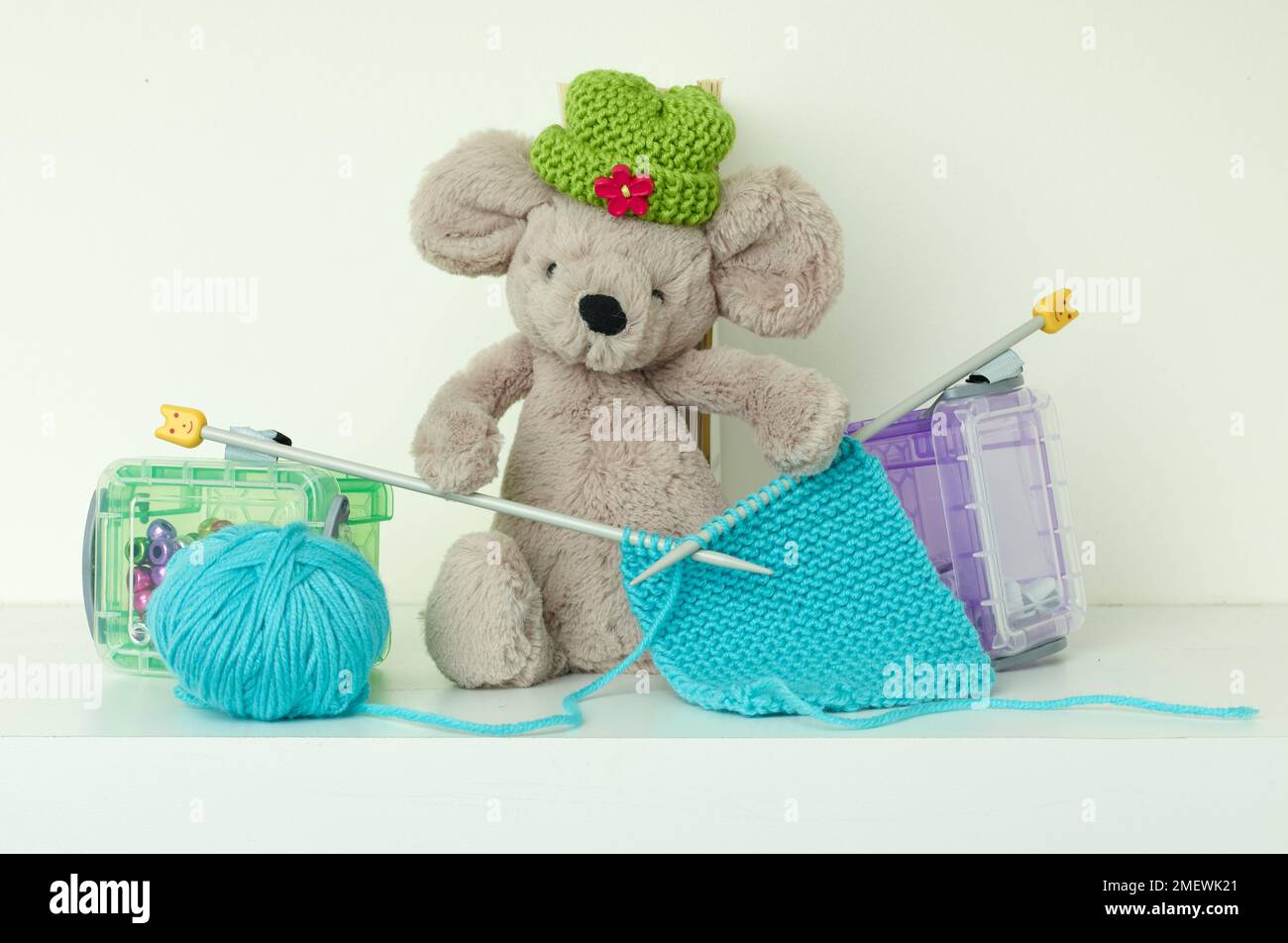 Mouse giocattolo con cappello verde in maglia, con aghi in maglia di lana blu Foto Stock