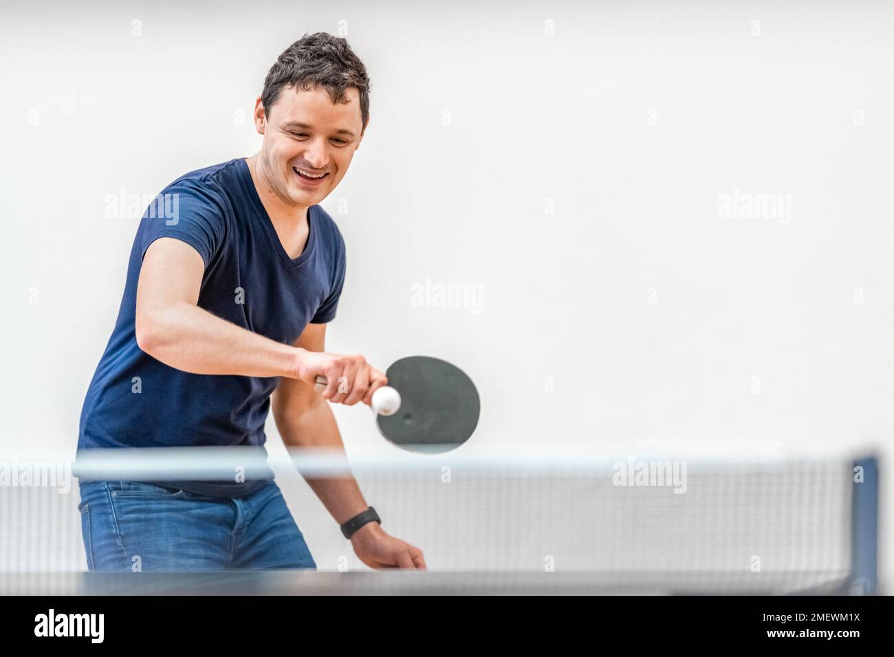 uomo che gioca a ping pong in palestra Foto Stock