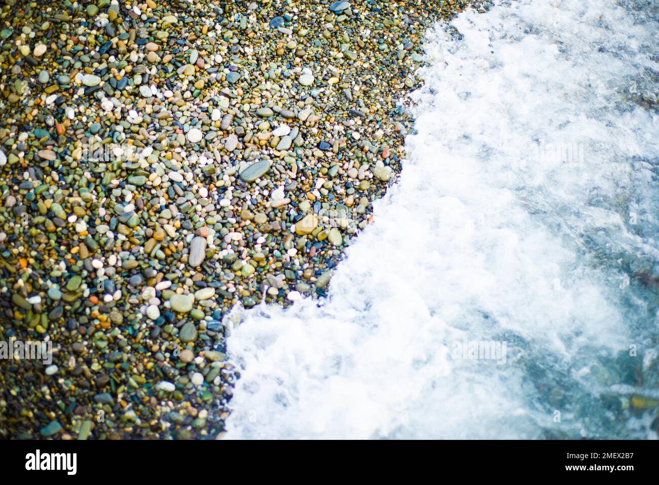 Schiuma di mare su una spiaggia di ciottoli. primo piano. Texture e sfondi marini. Due elementi. Foto Stock