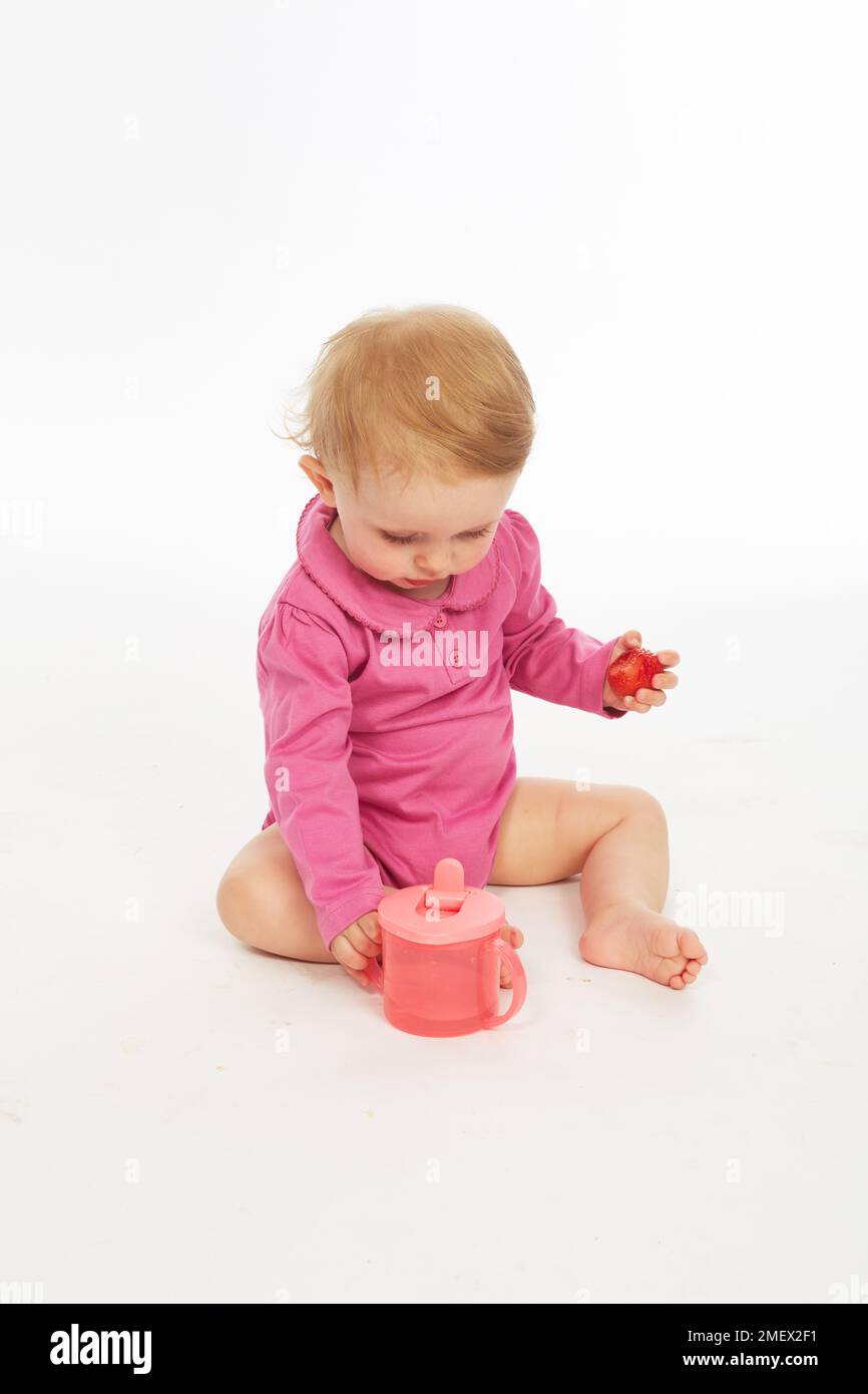 Baby in rosa playsuit bere (Modello età - 9 mesi) Foto Stock
