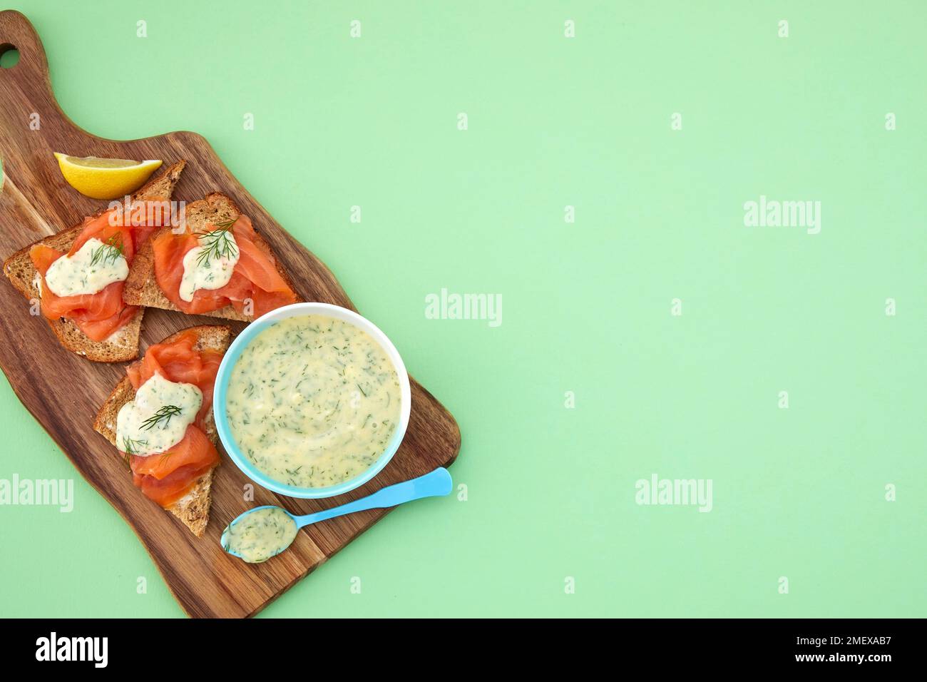 Salsa di senape dolce e aneto servita in piatto sul tritare con salmone sul pane Foto Stock