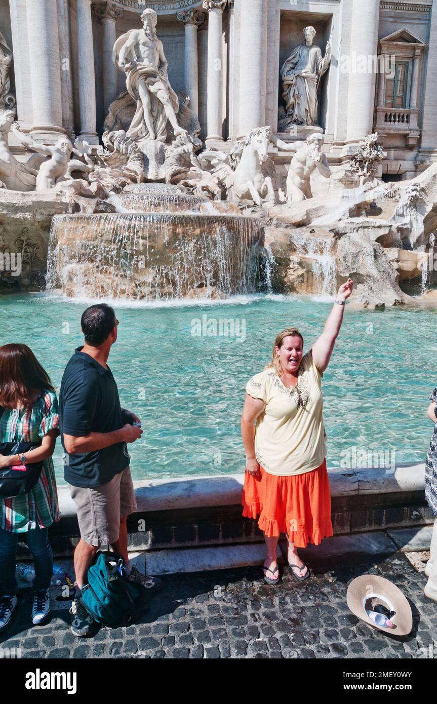 Una donna che si prepara a gettare le monete sulla spalla nella Fontana di Trevi a Roma Foto Stock