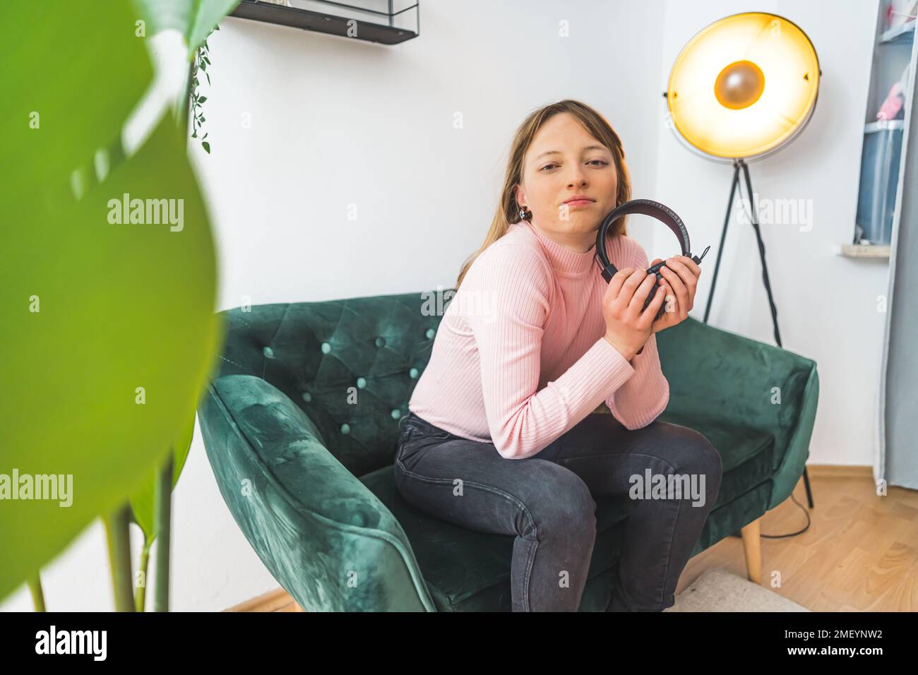 Giovane donna seduta su un divano con le cuffie in mano. Foto di alta qualità Foto Stock