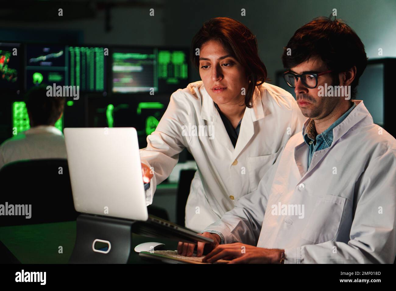 Due scienziati medici concentrati con camice di laboratorio analisi di un test di farmacia con un computer portatile. Un paio di medici che lavorano in un'indagine biologica. Concetto di scienza. Foto di alta qualità Foto Stock