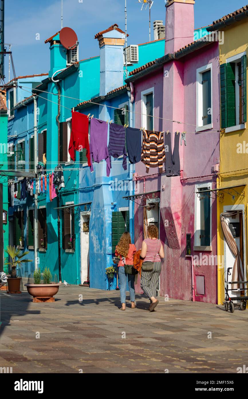Due donne che camminano sotto un bucato appeso nella colorata isola di Burano, in italia. Foto Stock
