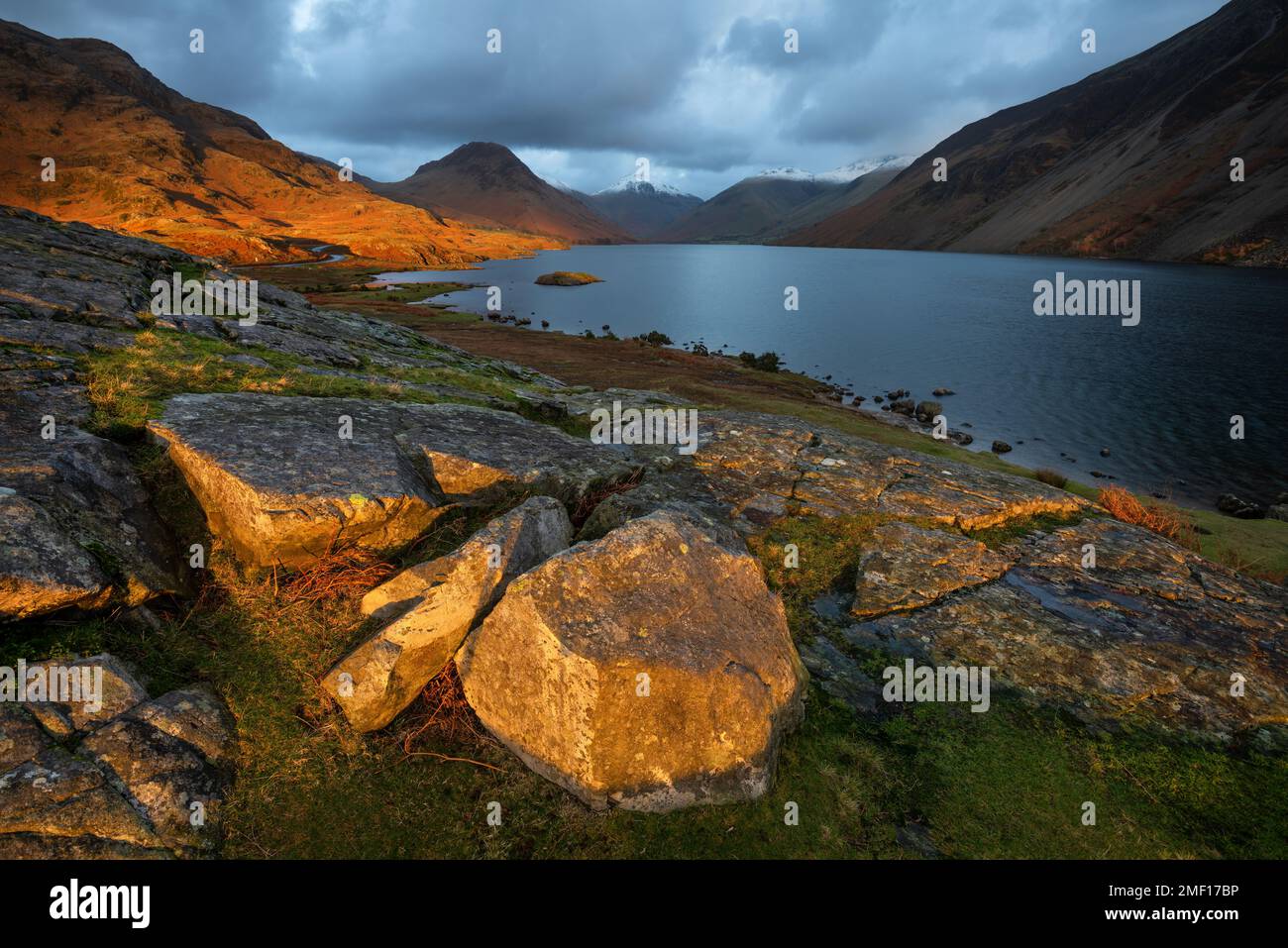 Spettacolare vista di Wastwater con nuvole scure e luce dorata sul paesaggio, Lake District, Regno Unito. Foto Stock