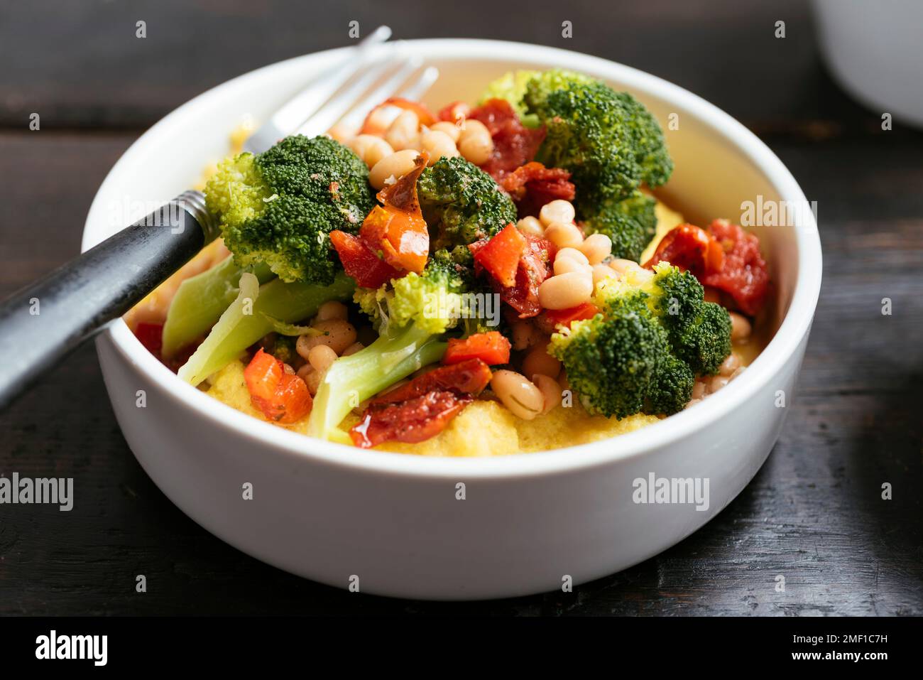Broccoli e fagioli alla polenta con pomodori secchi e peperoni. Foto Stock