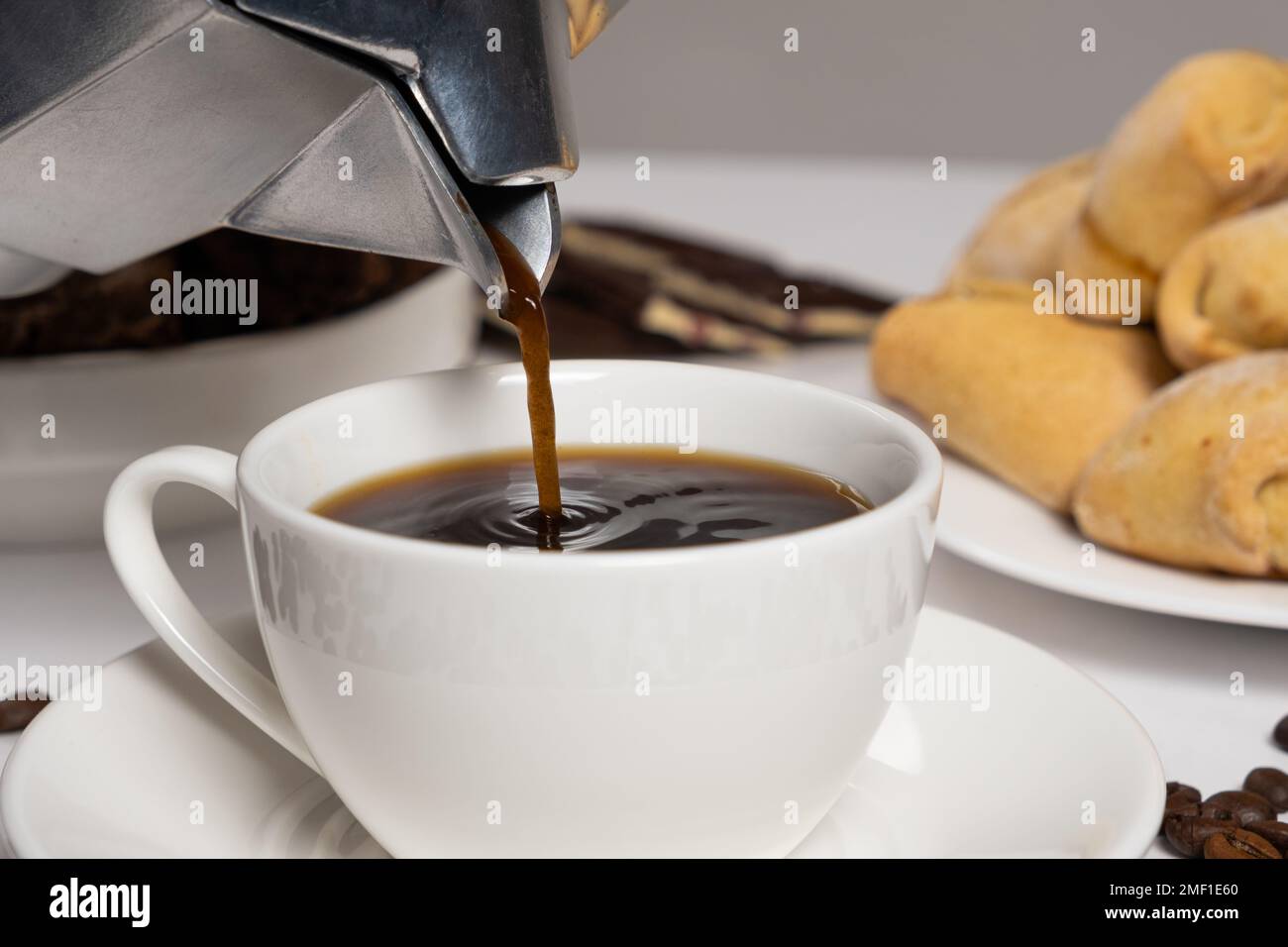 Il processo di versare il caffè da una macchina per il caffè geyser moka in una tazza bianca Foto Stock