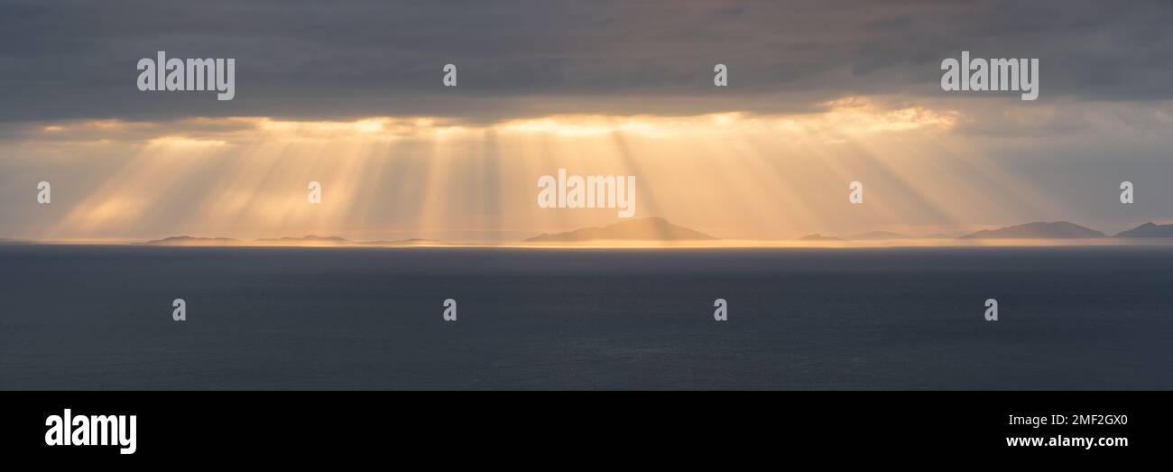 Raggi di sole mozzafiato che frenano attraverso nuvole buie e umide sopra le Ebridi esterne, Scozia, Regno Unito. Foto Stock