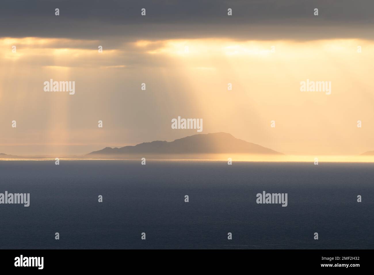 Raggi dorati di luce che brillano attraverso le nuvole in una serata celeste guardando verso le Ebridi esterne, visto dall'Isola di Skye, Scozia, Regno Unito. Foto Stock