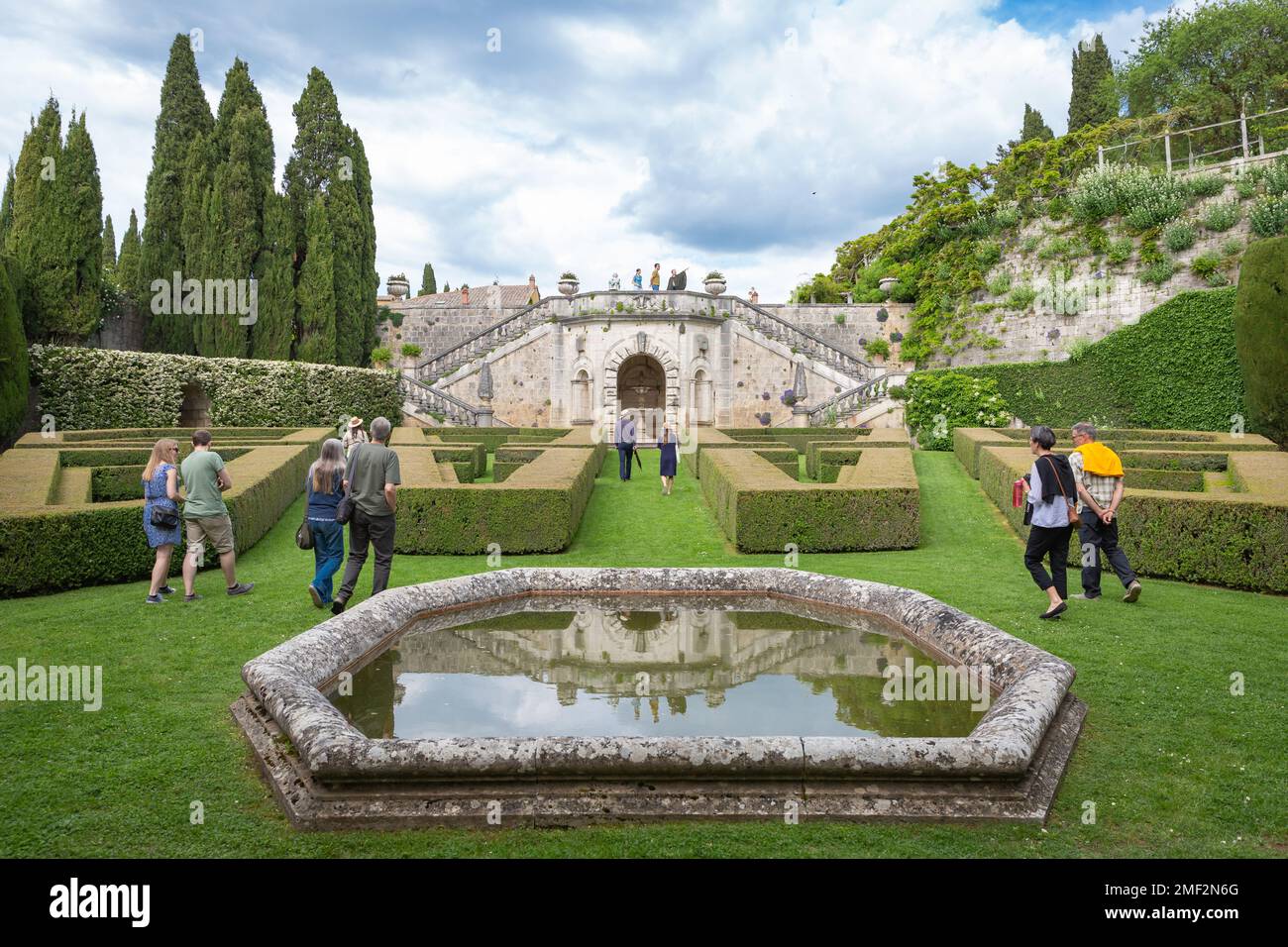 Persone che camminano attraverso i giardini in stile rinascimentale della tenuta la Foce, una storica residenza italiana toscana rivivuta da Antonino e Iris Origo. Foto Stock