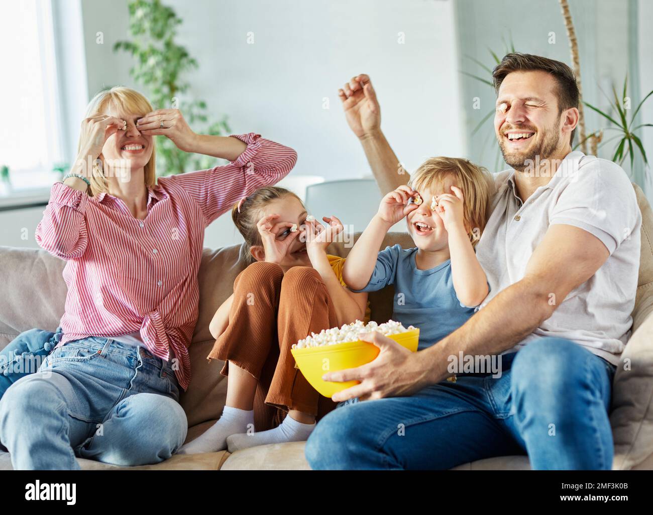 bambino figlia figlio famiglia felice madre padre divano divertimento insieme ragazza ragazzo tv film giocare intrattenimento guardare la televisione a casa insieme Foto Stock