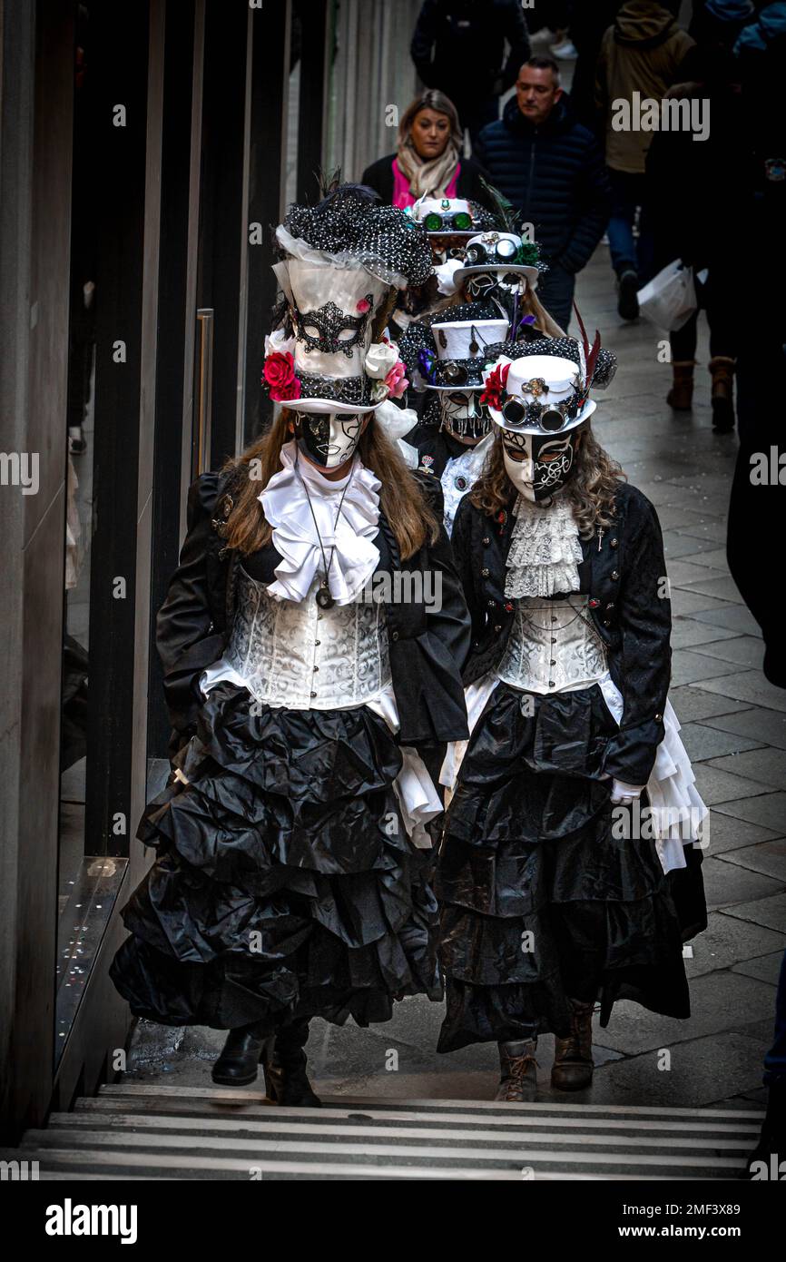 Un gruppo di ragazze vestite di abiti medievali e maschere carnevale camminano lungo la strada a Venezia, Italia Foto Stock