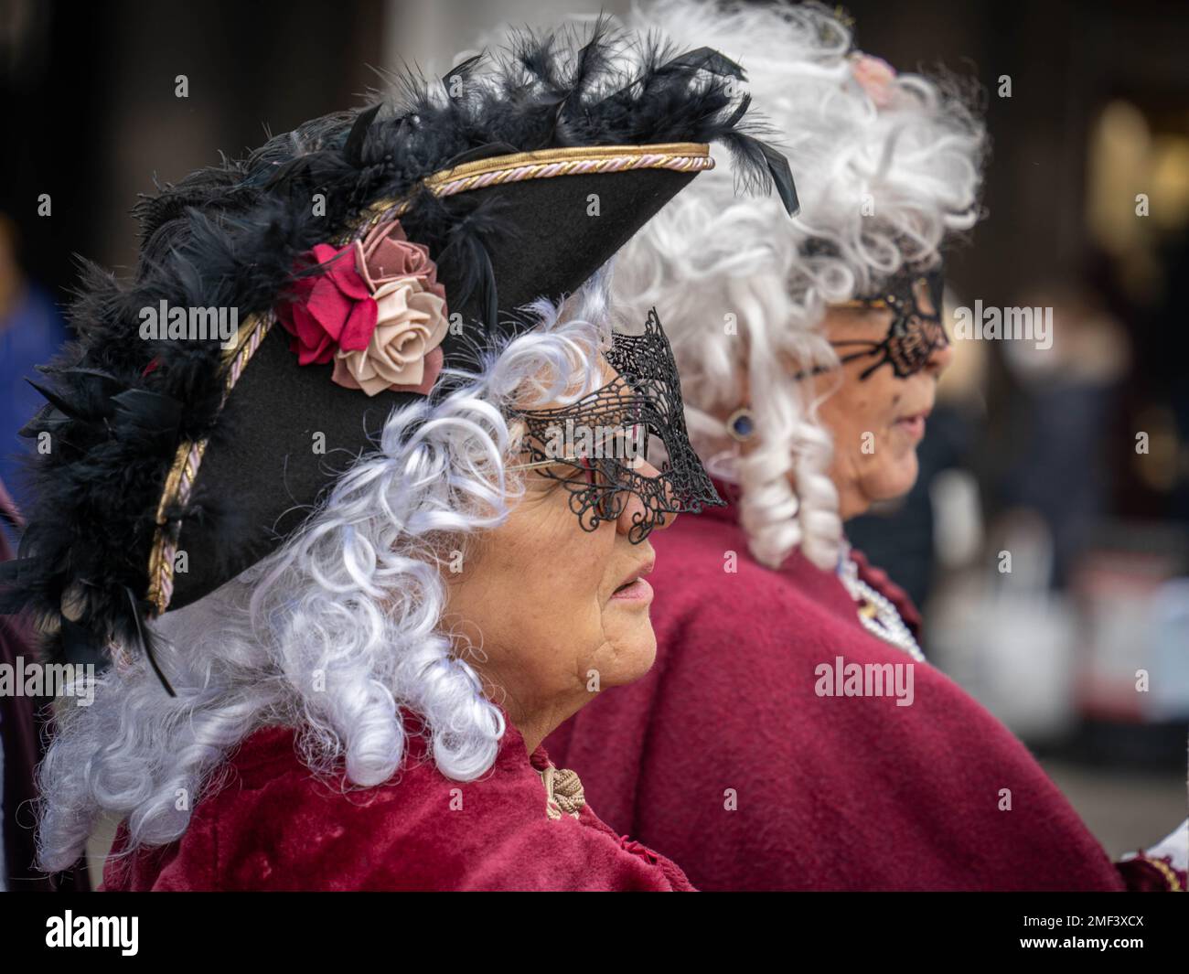 Facce di due donne adulte in cappelli, maschere, parrucche prese in profilo al carnevale di Venezia Foto Stock