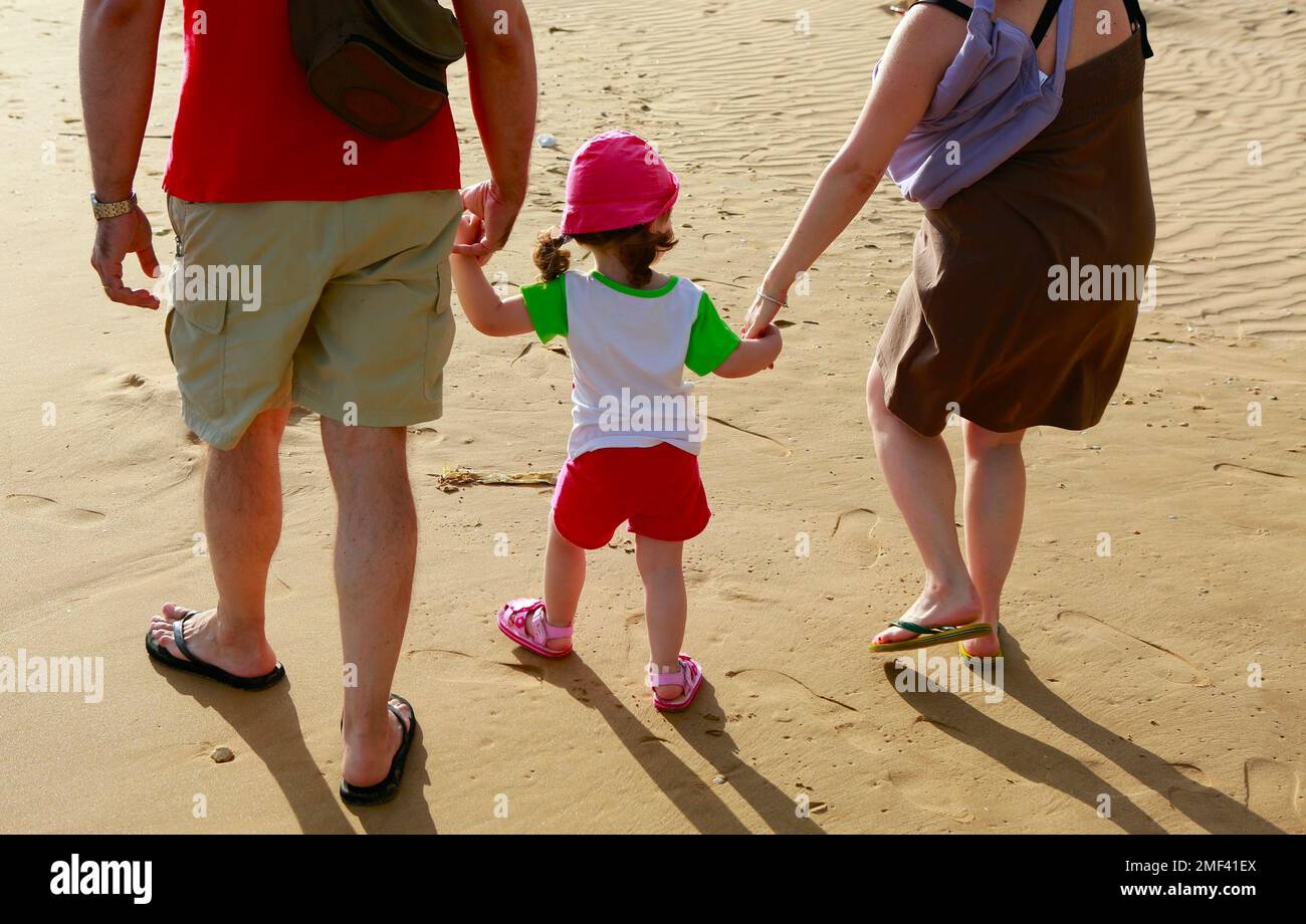 Una coppia che cammina con il bambino sulla spiaggia in Sicilia Foto Stock