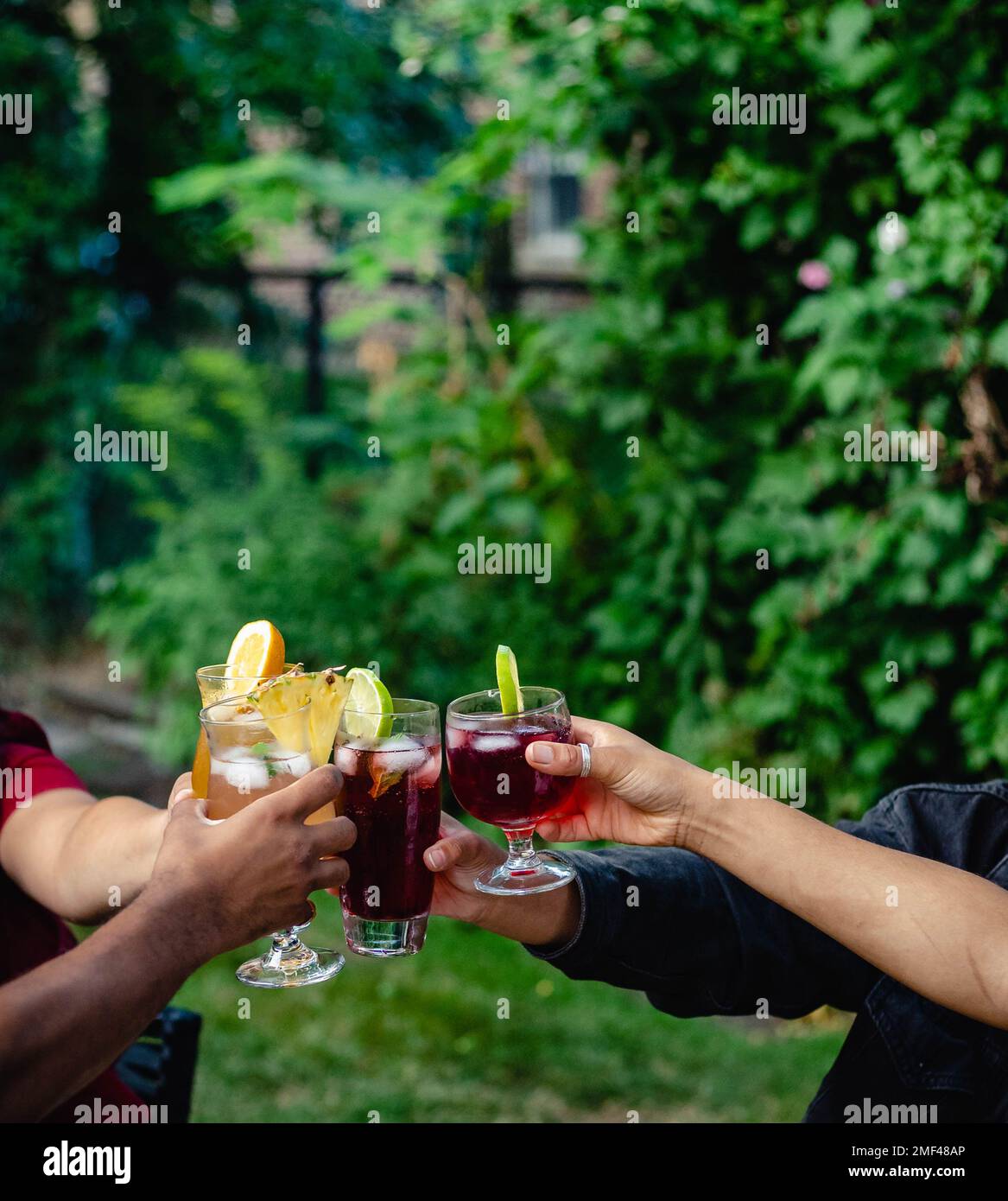 Quattro amici allietano i loro cocktail durante una cena sul cortile in estate Foto Stock