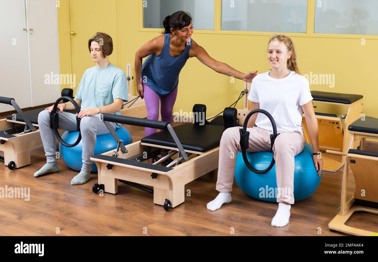 Gli adolescenti sotto la guida del trainer pilates sono impegnati con anello di ginnastica sulla sfera Foto Stock Gli adolescenti sotto la guida del trainer pilates sono impegnati con anello di ginnastica sulla sfera Foto Stock