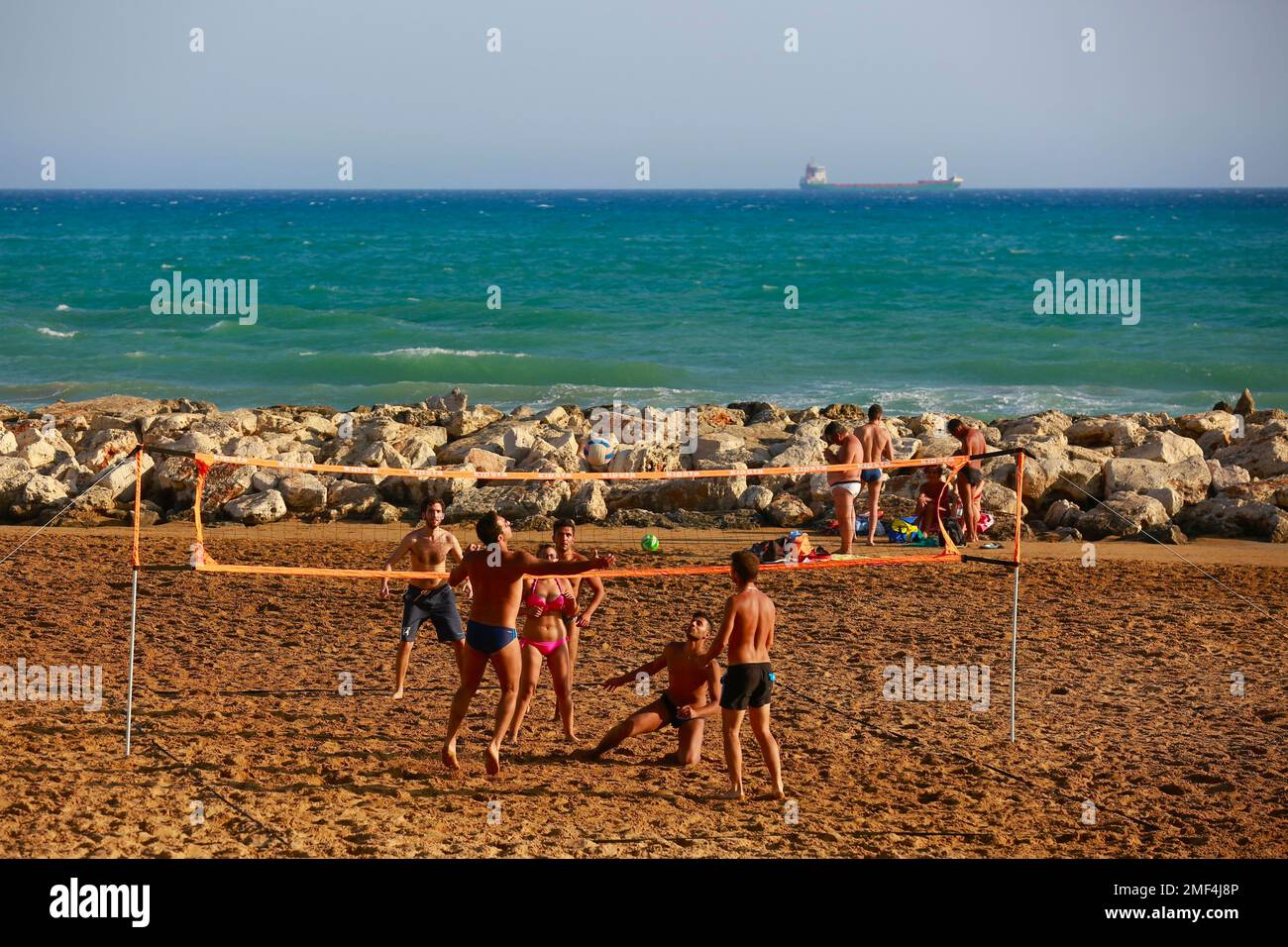 Giovani uomini che giocano a pallavolo sulla spiaggia in Sicilia Foto Stock