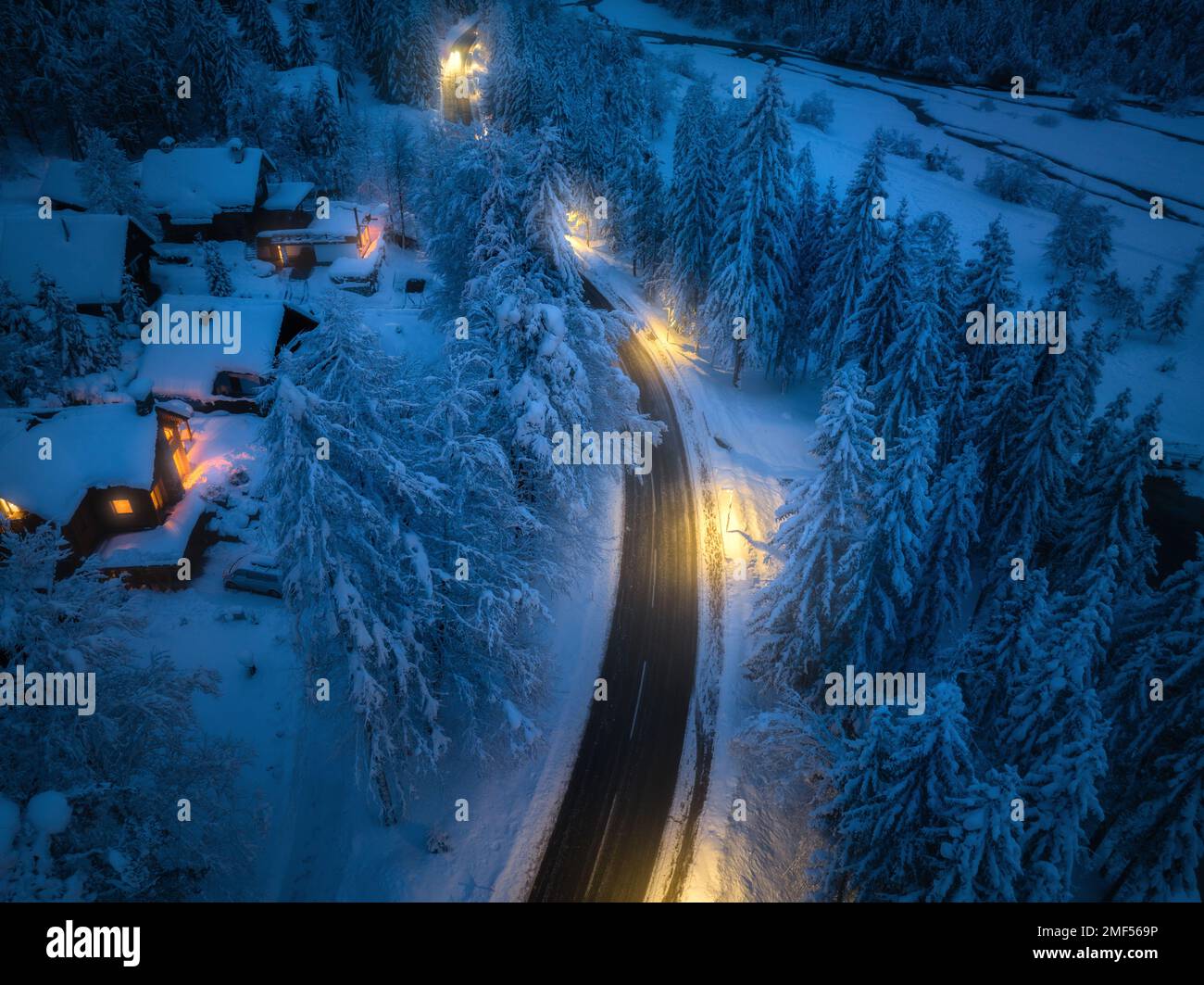 Veduta aerea della strada in città in neve, foresta, case di notte Foto Stock