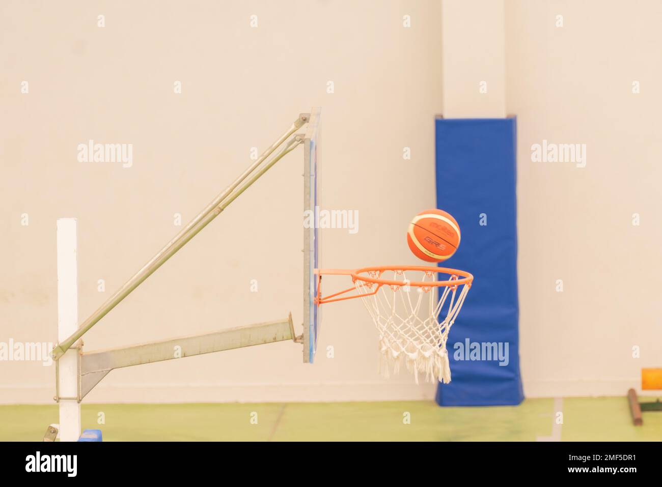 vista laterale di un basket che entra in un mini basket su un campo senza parquet, colore verde Foto Stock