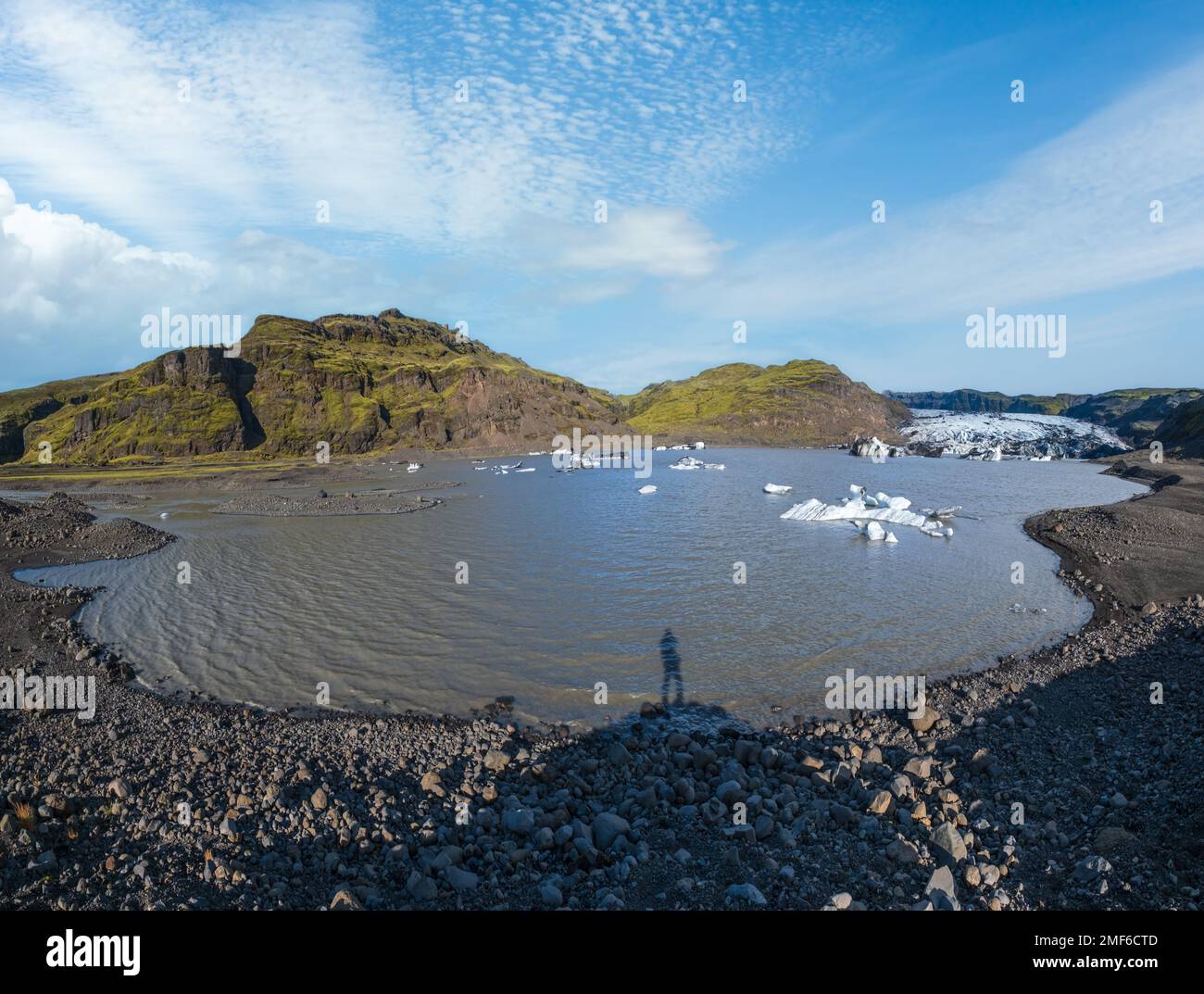 Ghiacciaio di Solheimajokull, Islanda. La sua lingua scorre dal vulcano Katla. Laguna glaciale del lago con blocchi di ghiaccio e montagne circostanti. Hill top e. Foto Stock