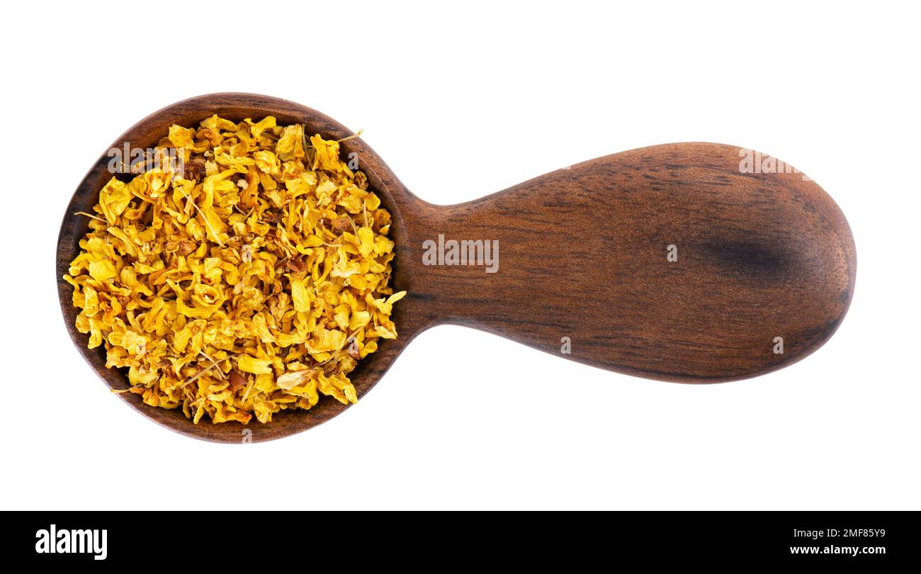 Tè di Osmanthus in cucchiaio di legno, isolato su fondo bianco. Fiori secchi di Osmanthus fragrans. Vista dall'alto Foto Stock
