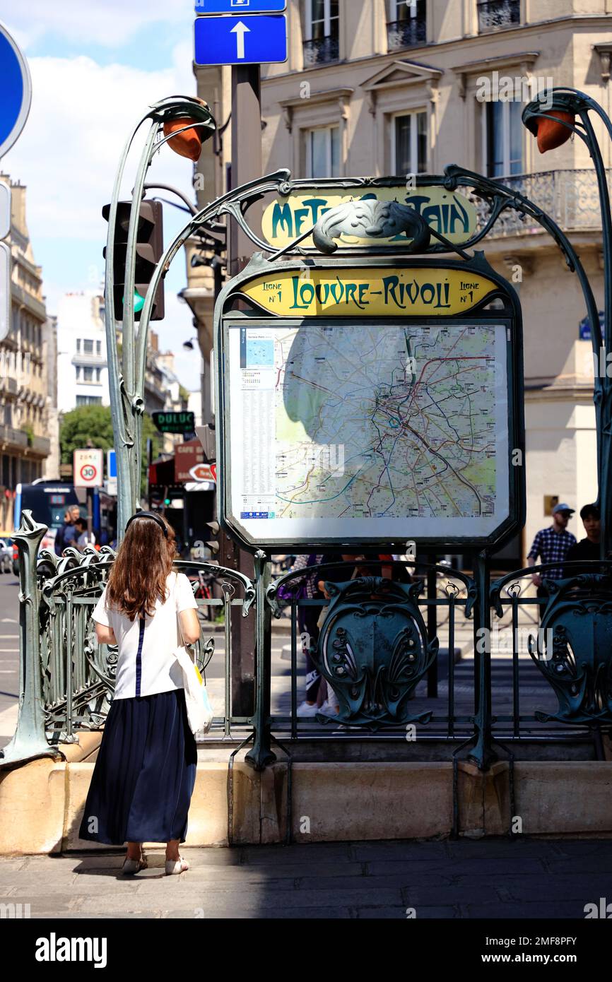 Un passeggero che guarda la mappa della metropolitana su una storica entrata Art Nouveau della stazione della metropolitana Louvre-Rivoli. Parigi, Francia Foto Stock