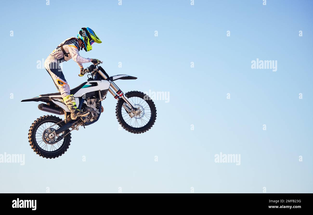 Moto, salto e persona su cielo blu beffa per l'allenamento, la concorrenza o sfida con gli attrezzi di sicurezza. Ciclismo professionale, moto e avventura Foto Stock