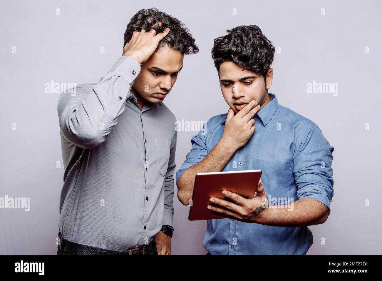 Triste disperato giovani manager maschi indiani guardando lo schermo del tablet, trovare errore negli account ufficio. Problemi di business, pianificazione del lavoro, finanza, dati Foto Stock