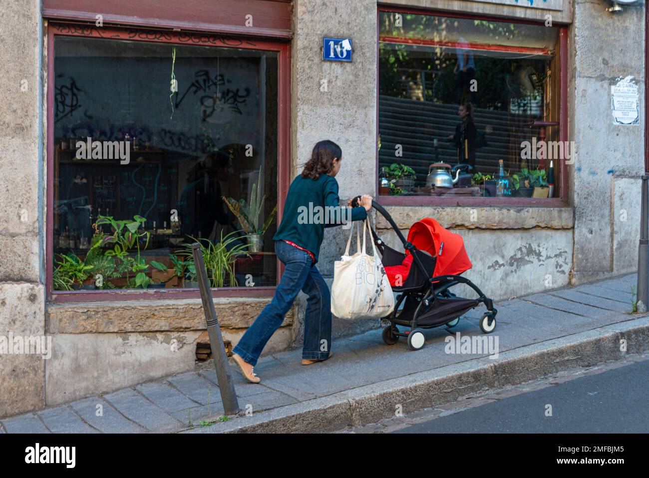 Mamma che spinge la carrozza del bambino su una delle molte colline ripide di Lione, Francia Foto Stock