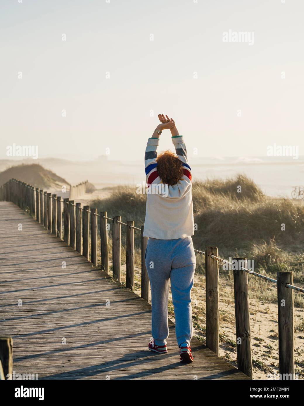 Donna matura esercizio al mattino, Donna adulta muscolo stretching contro dune di spiaggia, riscaldamento. Concetto di stile di vita attivo. Foto Stock